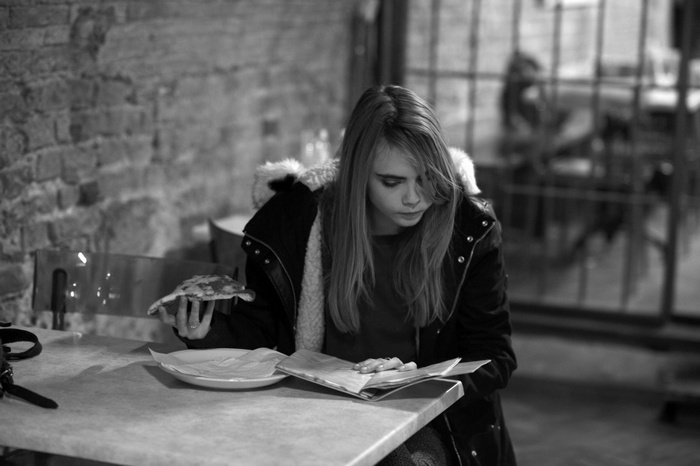 Cara Delevingne eating pizza and reading