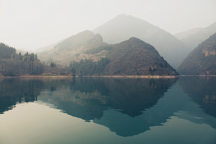 Misty mountains reflected in a calm lake