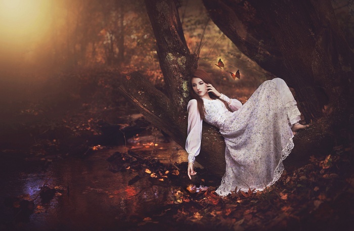 Woman in a white dress with butterflies in a forest