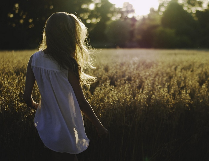 Girl in a white dress in a field at sunset