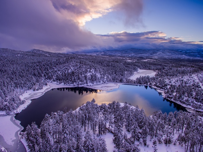 Snow-covered forest and lake at sunset