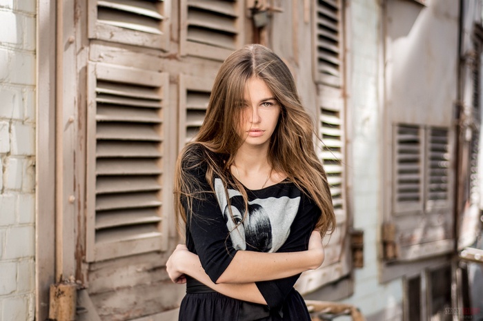 Woman with arms crossed in front of wooden shutters