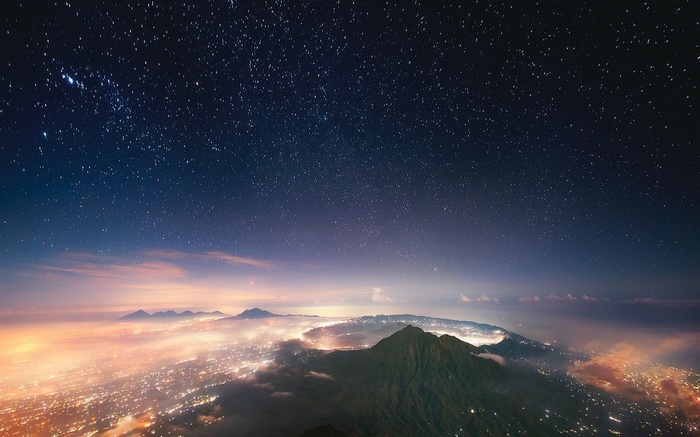 Starry night over Bali with city lights and mist