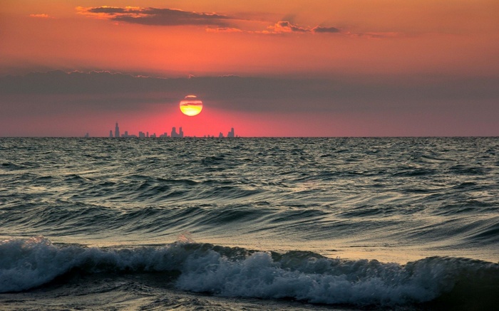 Sunset over the ocean with a distant cityscape