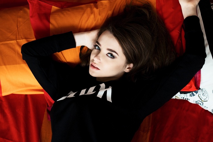 Woman with blue eyes and brunette hair lying on bed