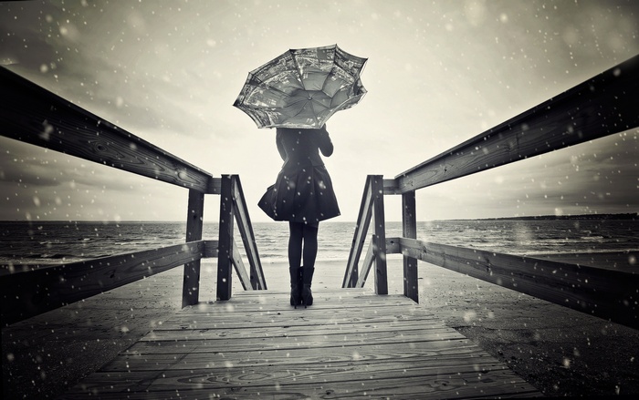 Woman with umbrella on a boardwalk in the rain