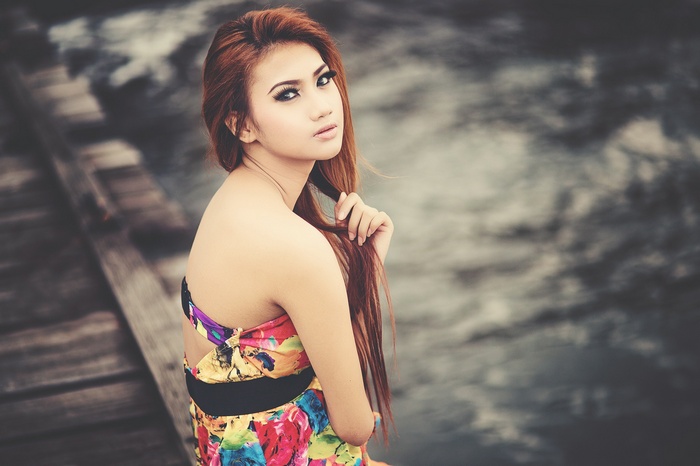 Asian woman with long brown hair on a wooden pier