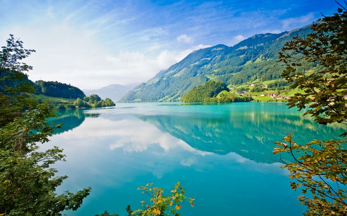Turquoise lake surrounded by green mountains and trees