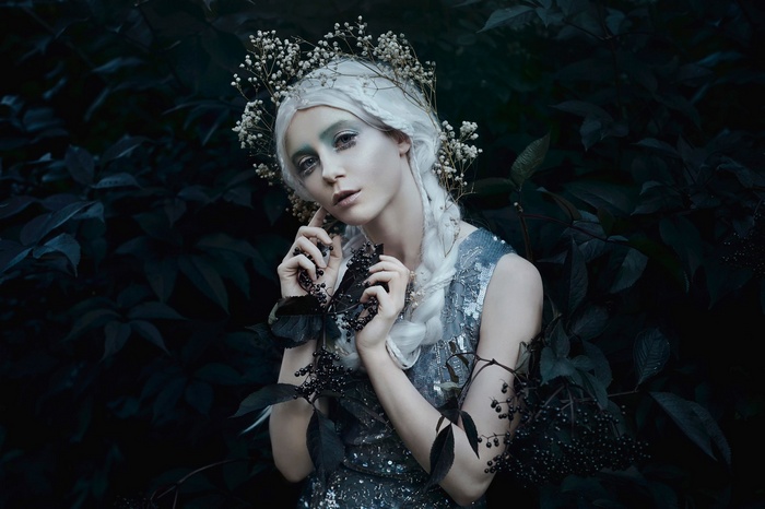 Woman with white hair and flower crown holding berries