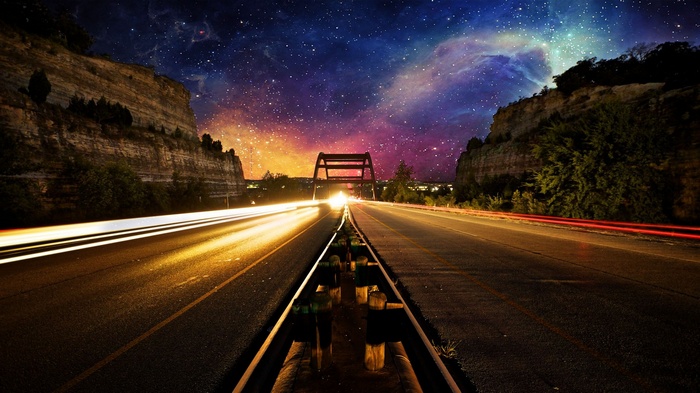 Road with light trails under a starry nebula sky