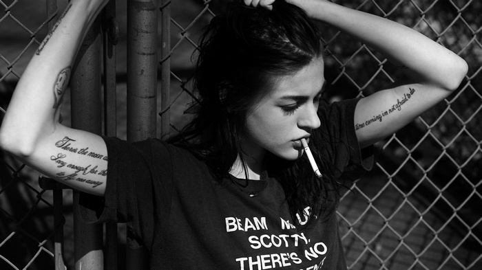 Frances Bean Cobain smoking by a fence