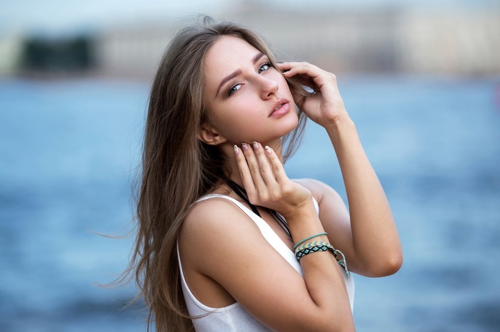 Woman with long brown hair posing by the water
