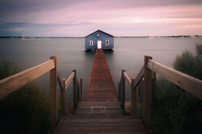Blue boathouse on a calm lake at sunset
