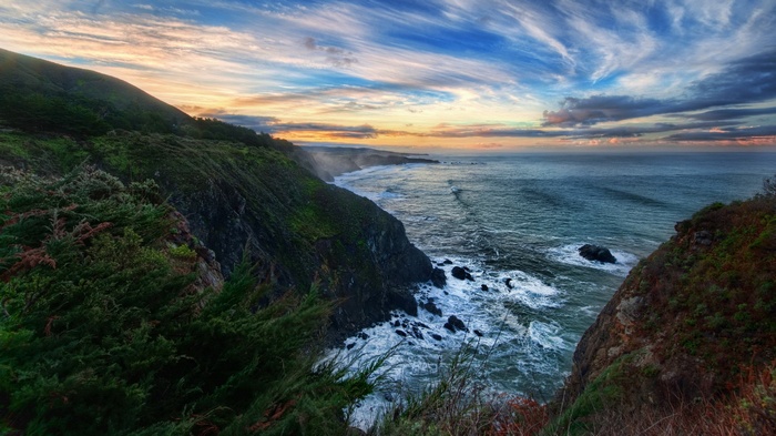 Coastal cliffs and ocean at sunset with dramatic clouds