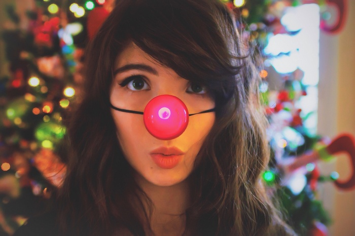 Woman with a red nose in front of a Christmas tree