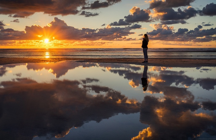 Person watching sunrise over the ocean with reflection