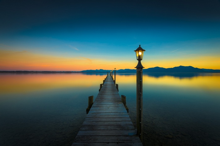 Wooden pier with lamps on a lake at sunset