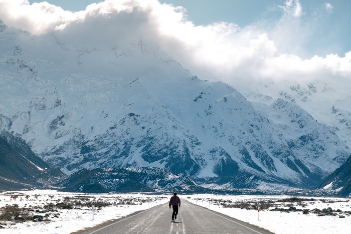 Person skateboarding on a road with snowy mountains