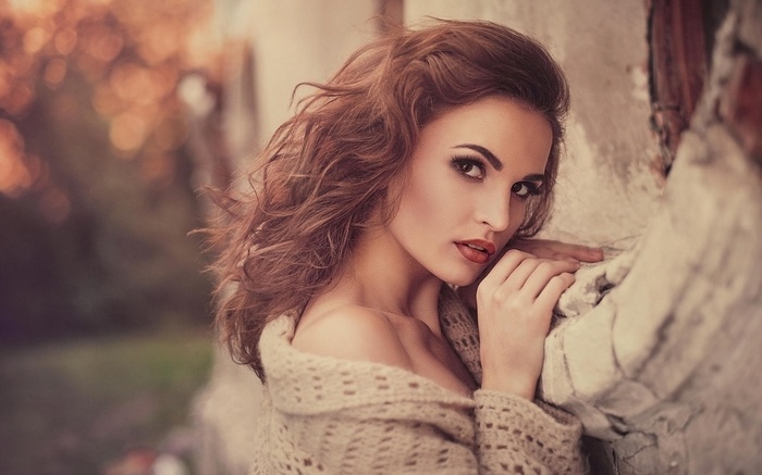 Julia Sariy with auburn wavy hair wearing a sweater