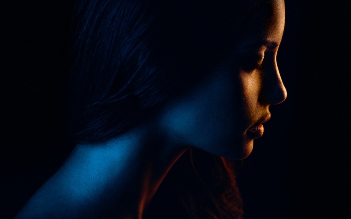 Woman's face illuminated by blue and orange lights