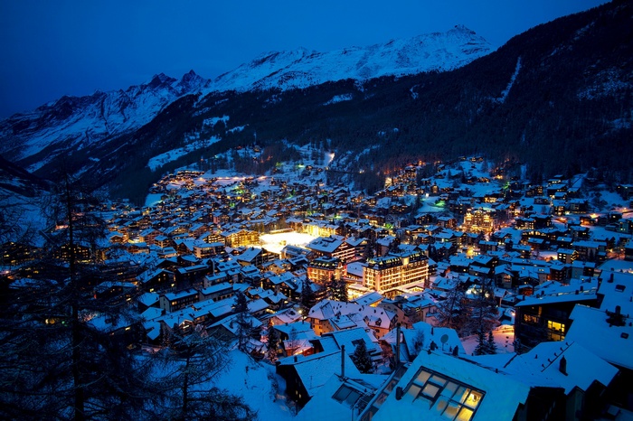Winter village nestled in snowy mountains at night