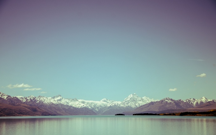 Snow-capped mountains reflected in a calm lake in New Zealand