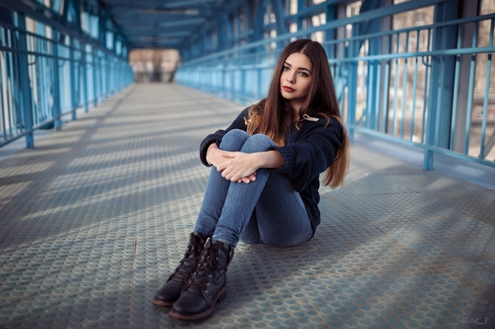 Woman sitting on a bridge holding her knees