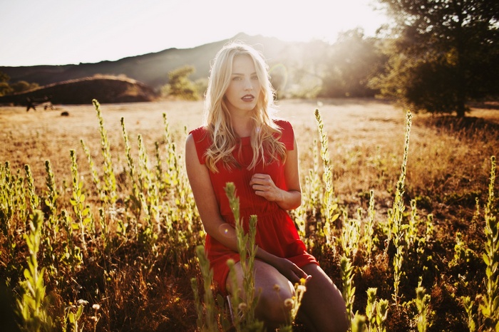 Woman in red dress in a field at sunset