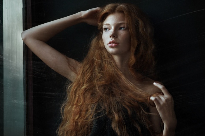 Redhead woman with long wavy hair by the window
