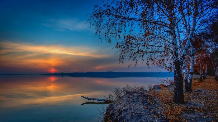 Sunset over a calm lake with birch trees in Russia
