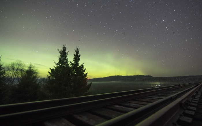Aurora Borealis over railway tracks and trees