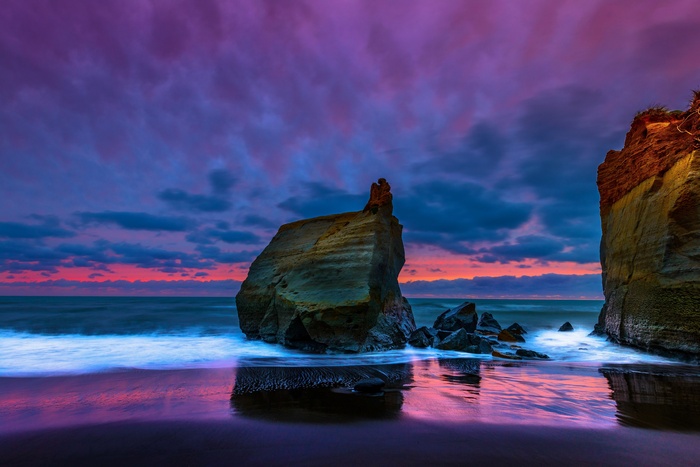 Dramatic sunset over a rocky coastline with crashing waves