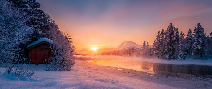 Winter sunrise over a snowy landscape with a cabin