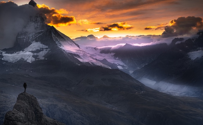Hiker on a peak overlooking the Matterhorn at sunset