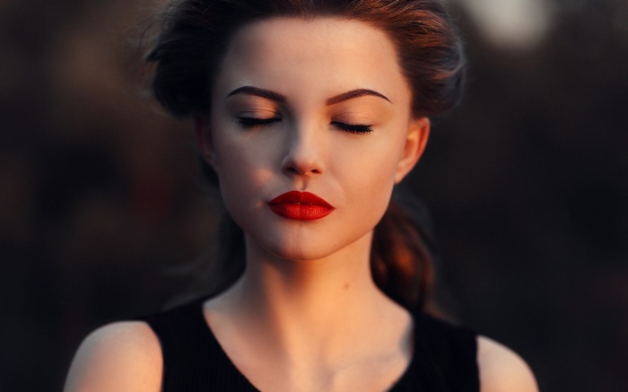 Woman with closed eyes and red lipstick outdoors