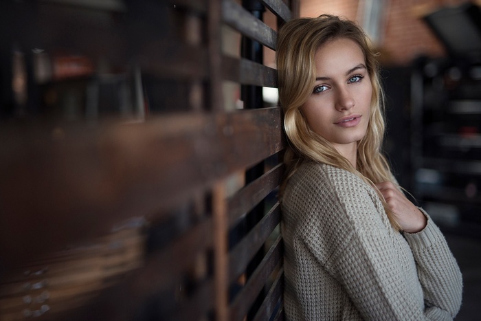 Woman with blonde hair leaning against a wooden structure