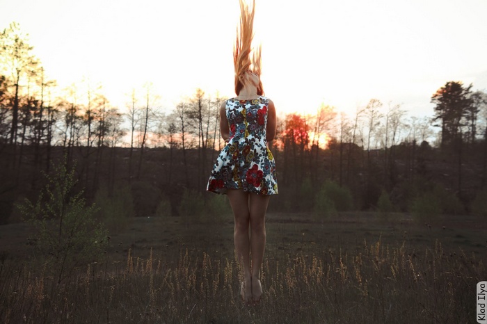 Woman with long hair in a floral dress in a field