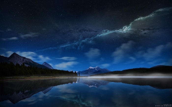 Night sky over a misty lake and mountains