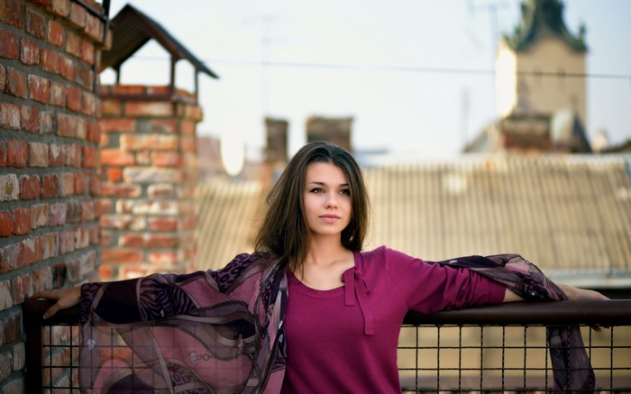 Woman with long hair on a balcony with brick wall