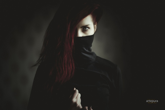 Woman with red hair wearing a black turtleneck and mask