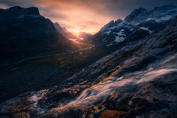 Sunlight over a valley with mountains and a river in Greenland