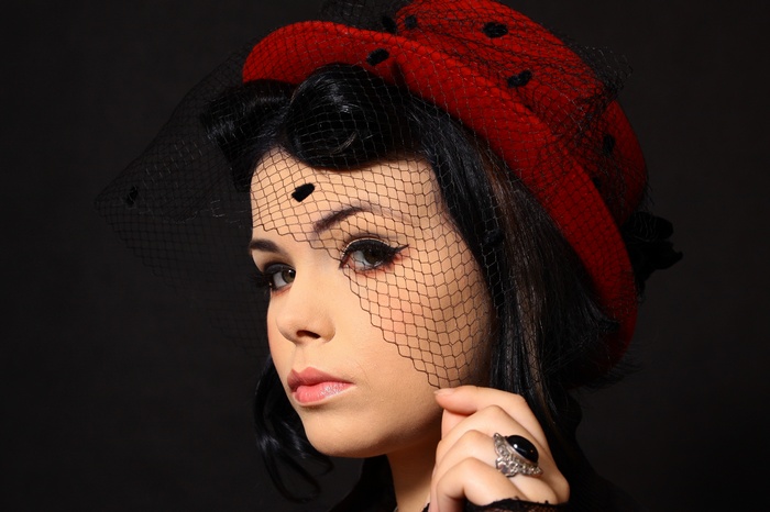 Woman in red hat with black veil and ring