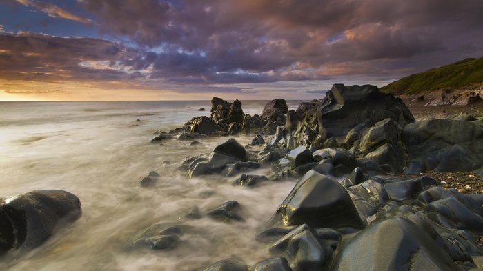 Rocky coastline with ocean waves at sunset