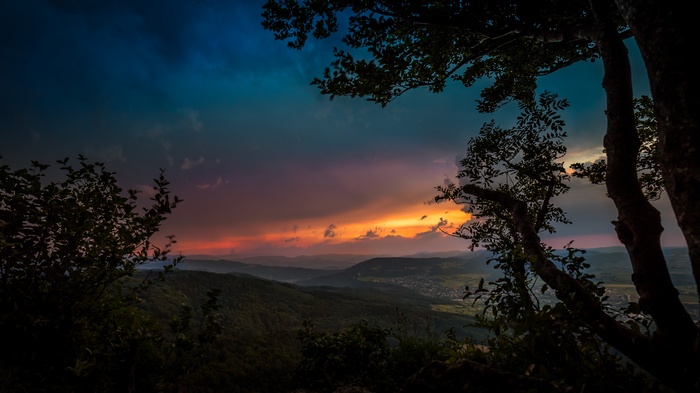 Sunset over a valley with trees in the foreground
