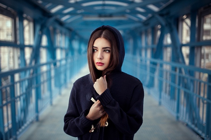 Woman in a dark hoodie on a blue bridge