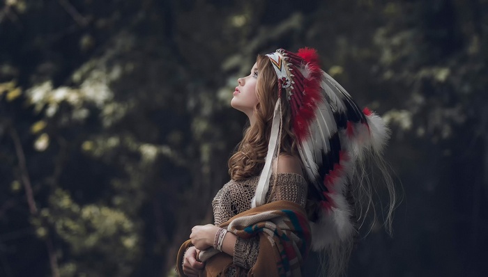 Woman wearing Native American headdress in forest
