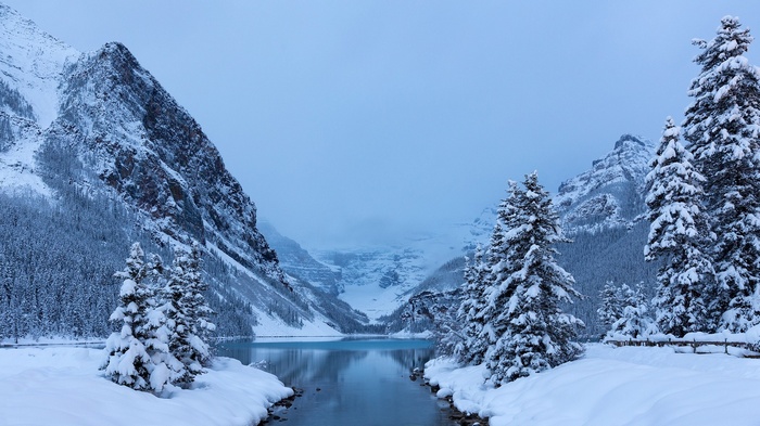 Snowy mountain landscape with a lake and pine trees