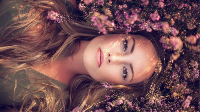 Woman with blonde hair lying in flowers