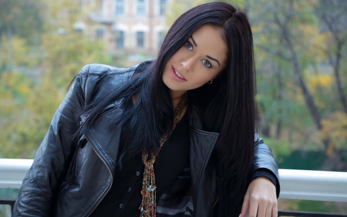 Macy B wearing a black leather jacket on a balcony