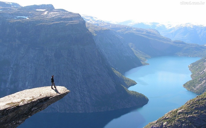 Person standing on Trolltunga cliff overlooking a fjord
